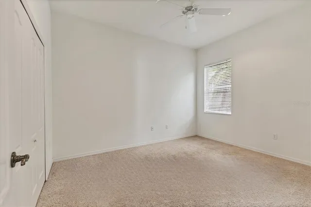 an empty room with a ceiling fan and a window