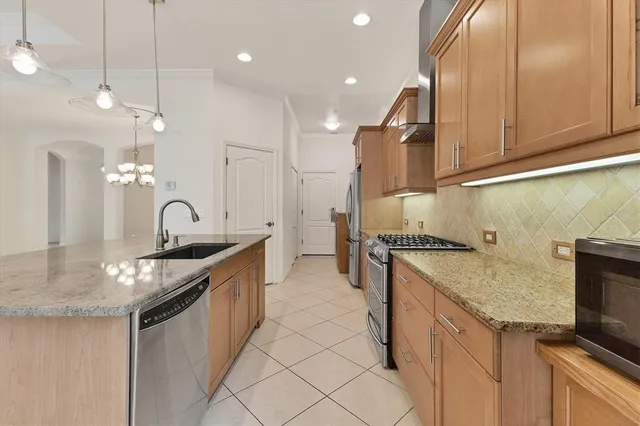 a kitchen with stainless steel appliances granite countertop a sink a stove and a refrigerator