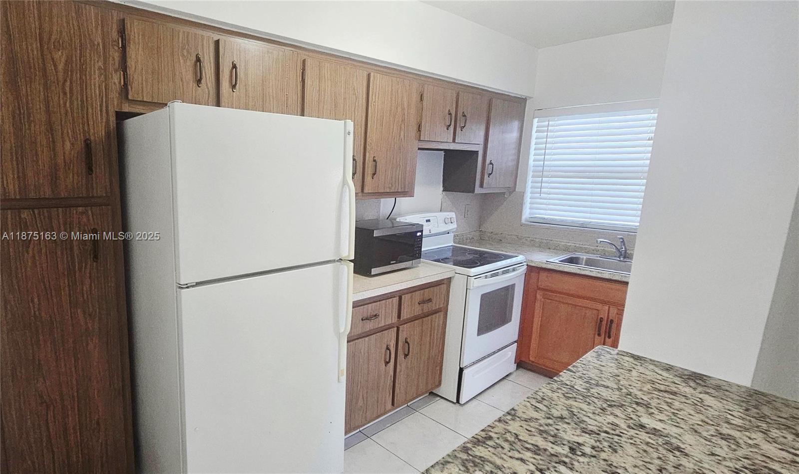 141 Northeast 10th Avenue, Unit 22C Hallandale Beach, FL 33009 - Photo 12 of 16 a white refrigerator freezer sitting inside of a kitchen