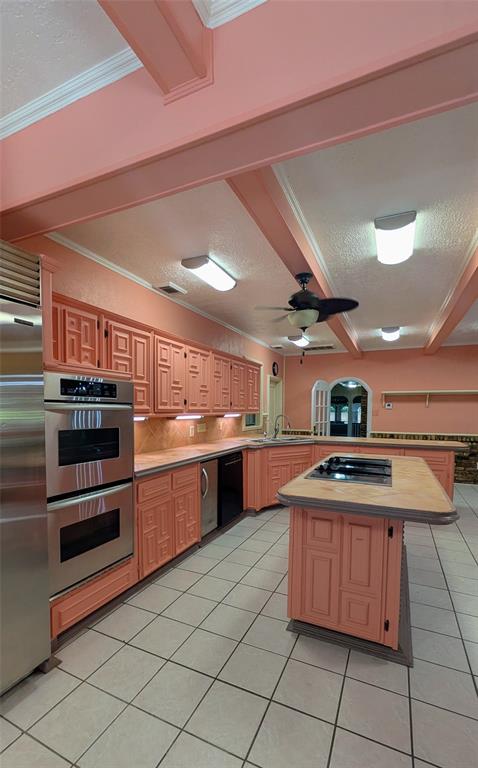 1431 South Houston School Road Lancaster, TX 75146 - Photo 24 of 39 Kitchen featuring extensive cabinetry with decorative paneling, a large center island with cooktop, and stainless steel built-in double ovens