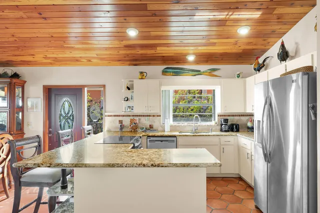 a kitchen with stainless steel appliances granite countertop a sink a stove cabinets counter space and a dining table