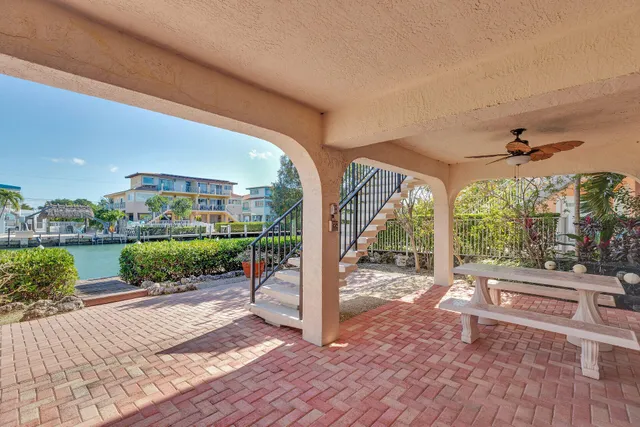 a view of a patio with a table chairs potted plants and palm trees