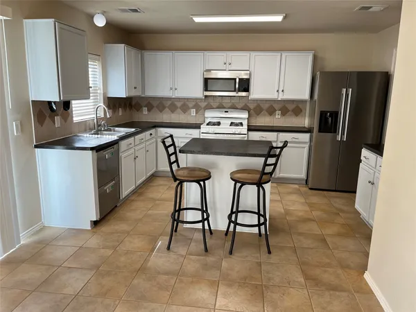 a kitchen with stainless steel appliances granite countertop a stove a sink a microwave and a refrigerator