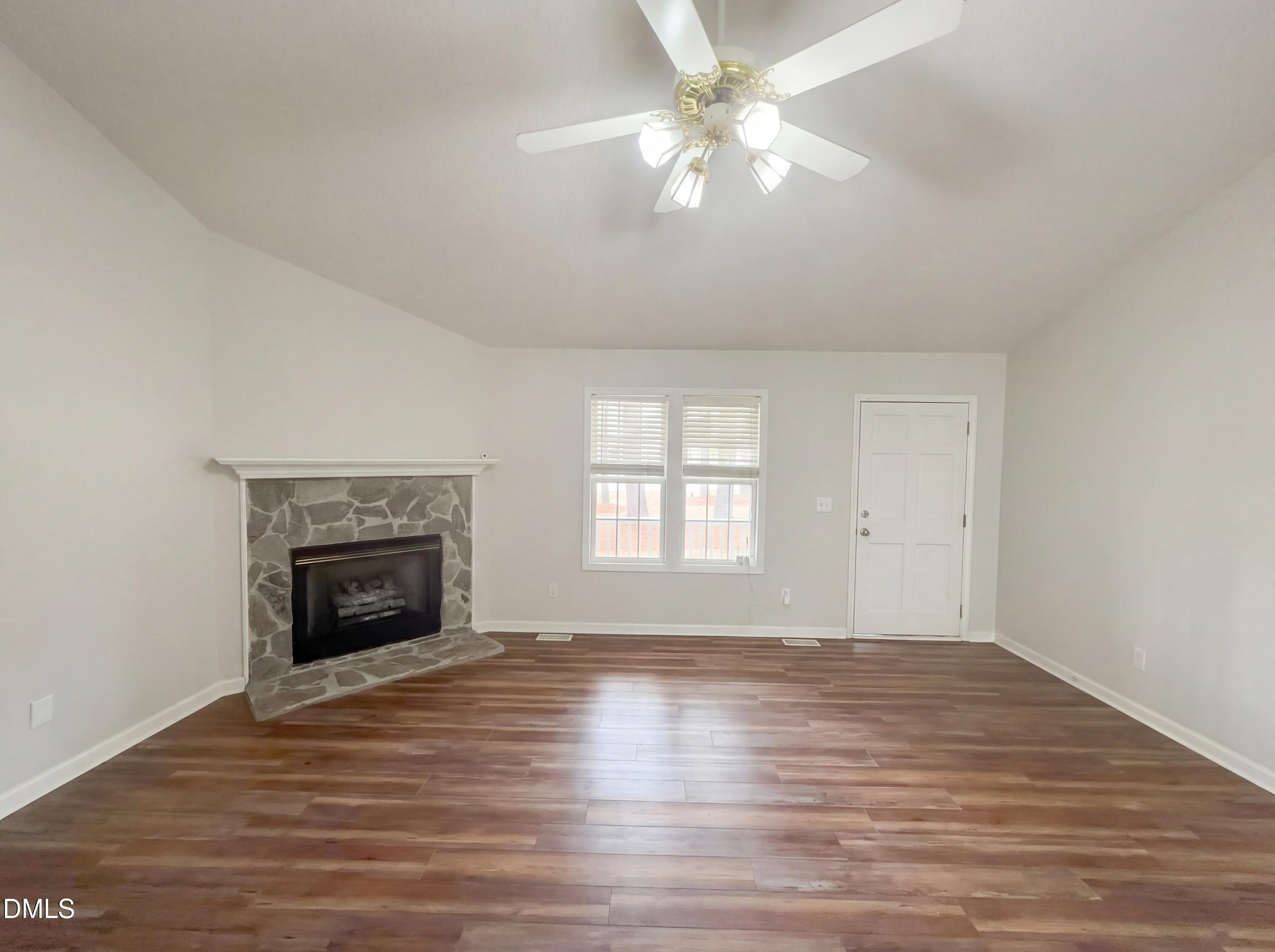 299 Greenleaf Road Angier, NC 27501 - Photo 3 of 15 an empty room with wooden floor fireplace and fan