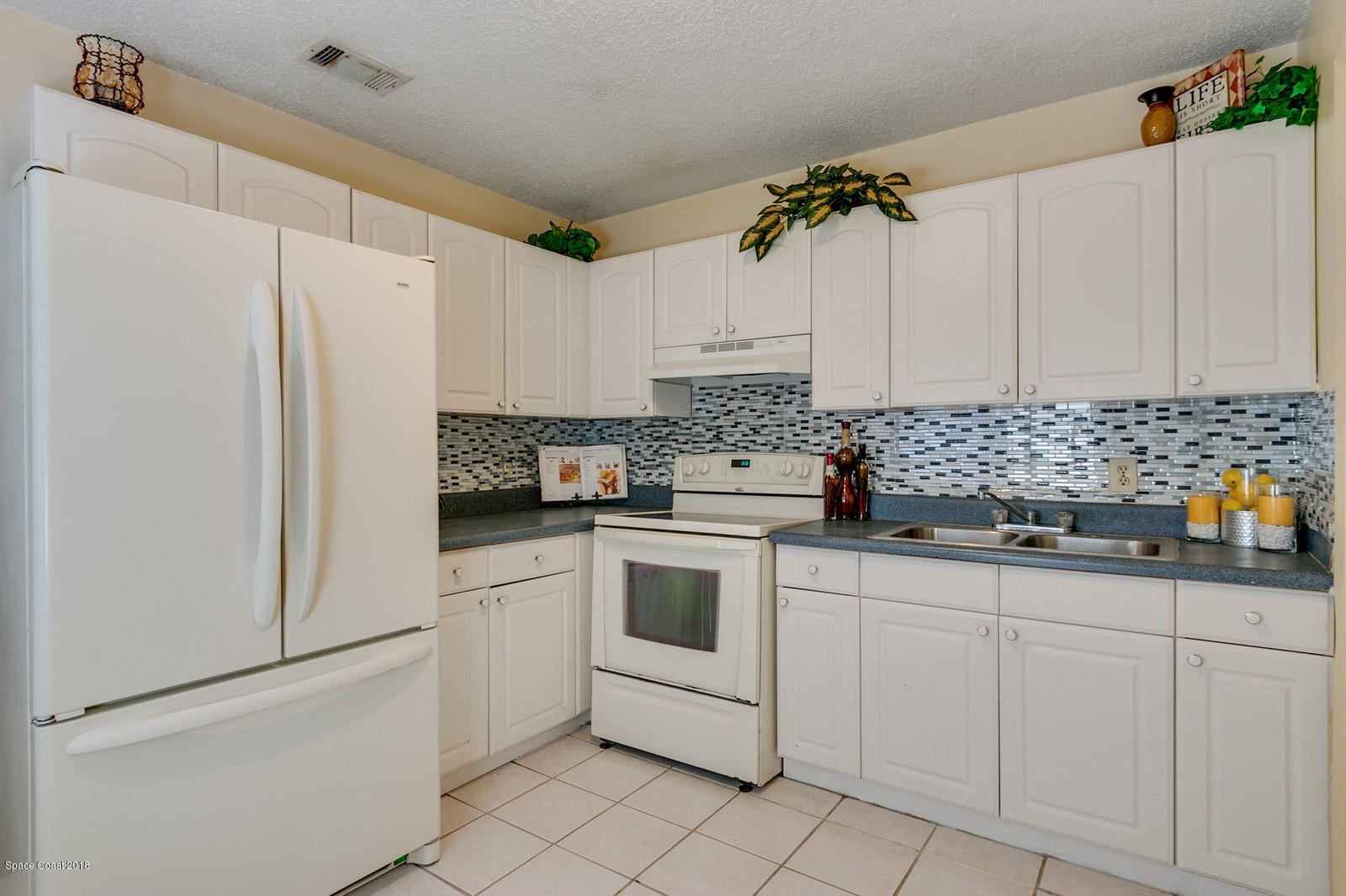 1586 Creel Road Northeast Palm Bay, FL 32905 - Photo 8 of 21 a kitchen with white cabinets and white appliances
