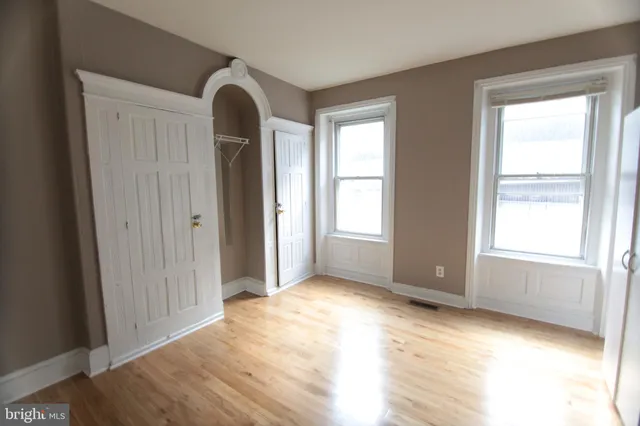an empty room with wooden floor and windows