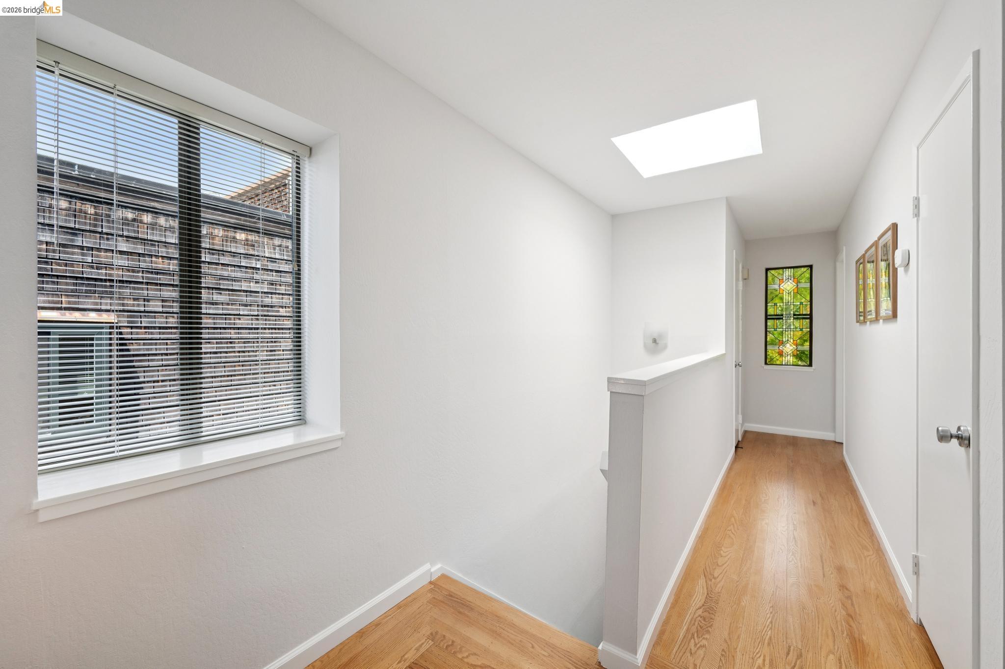 1340 Henry Street Berkeley, CA 94709 - Photo 33 of 52 Hallway featuring wood-finish flooring, a skylight, and multiple windows with blinds