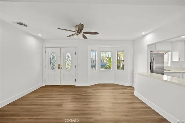 a view of empty room with wooden floor and fan