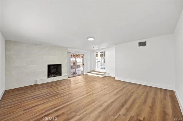 a view of empty room with wooden floor and fireplace