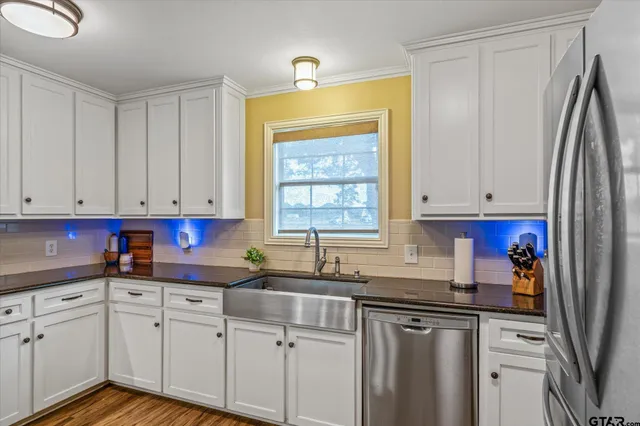 a kitchen with stainless steel appliances granite countertop a sink a refrigerator and cabinets