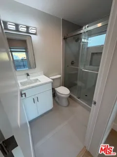 a bathroom with a sink a toilet a mirror and shower