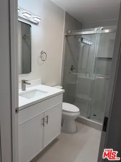 a bathroom with a shower sink vanity and toilet