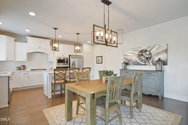 a kitchen with stainless steel appliances kitchen island granite countertop a table chairs and white cabinets