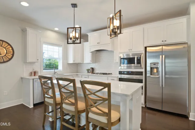 a kitchen with stainless steel appliances granite countertop a kitchen island a stove a table and chairs