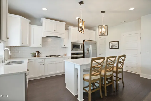 a kitchen with stainless steel appliances kitchen island granite countertop a table chairs and white cabinets