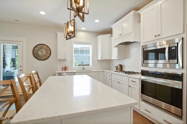 a kitchen with stainless steel appliances granite countertop a sink a stove top oven a clock and cabinets