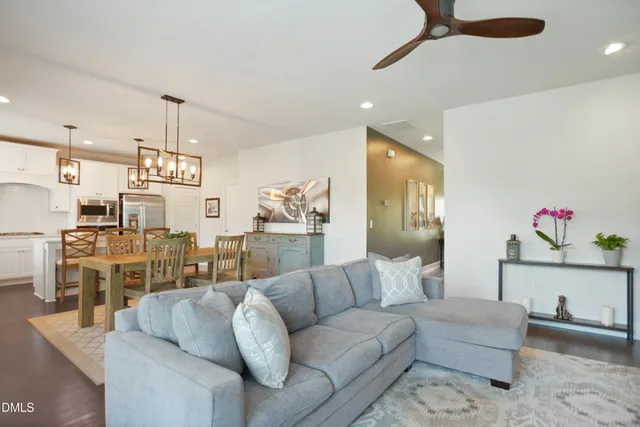 a living room with furniture kitchen view and a chandelier
