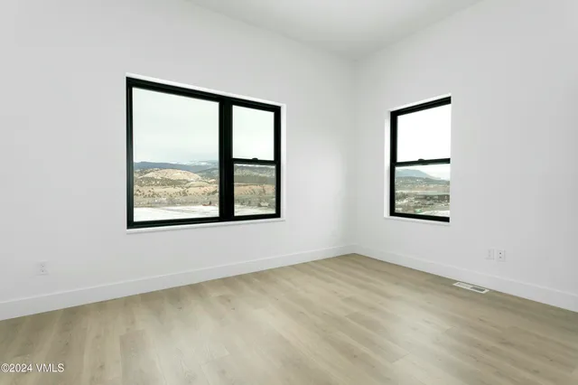 a view of an empty room with wooden floor and a bathroom