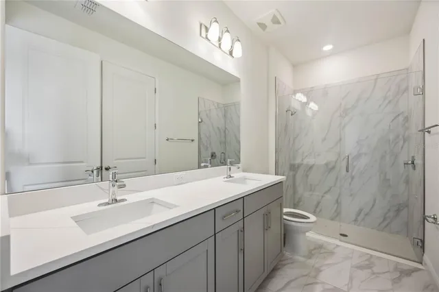 a bathroom with a sink double vanity granite toilet and a shower