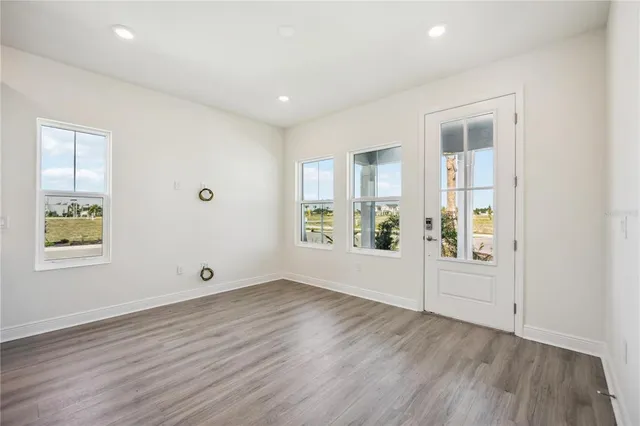 an empty room with wooden floor and windows