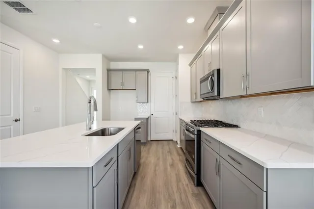 a kitchen with stainless steel appliances granite countertop a sink stove and cabinets