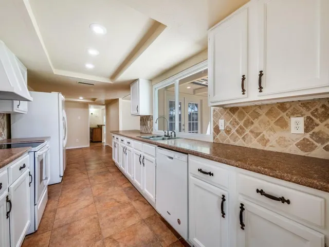 a large white kitchen with granite countertop a sink