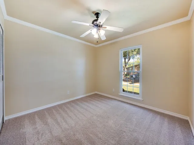 an empty room with window and ceiling fan