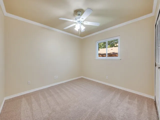 an empty room with a chandelier fan and windows
