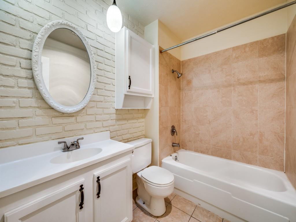 5044 Brandenburg Lane The Colony, TX 75056 - Photo 28 of 33 Full bathroom with vanity, shower / bathtub combination, light tile patterned floors, brick wall and decorative lighting.