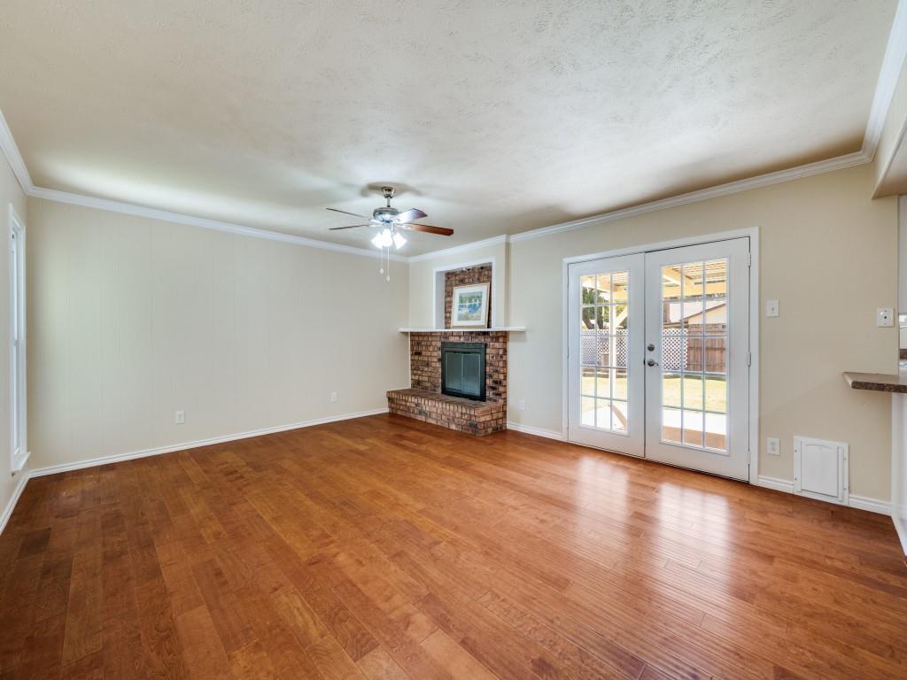 5044 Brandenburg Lane The Colony, TX 75056 - Photo 9 of 33 Cozy family room featuring crown molding, a ceiling fan, french doors, a gas fireplace, and light wood finished floors
