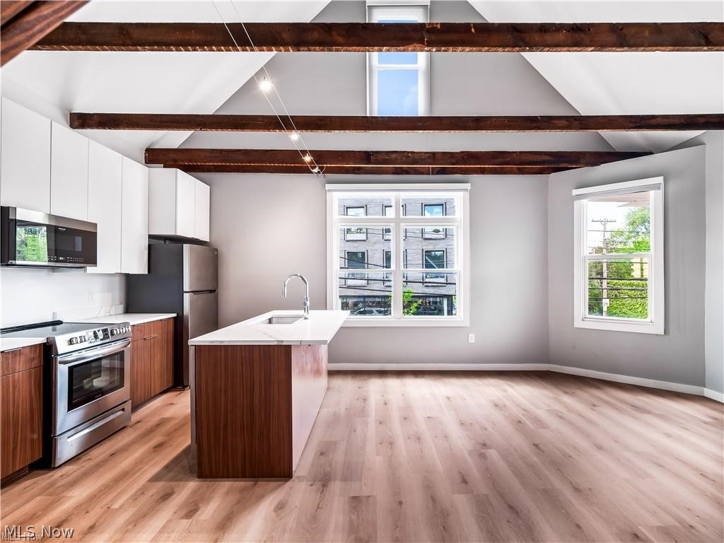 2401 Scranton Road, Unit A Cleveland, OH 44113 - Photo 2 of 17 Open-concept living space featuring exposed ceiling beams and wood-finish flooring