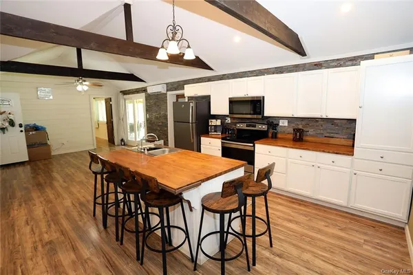 a kitchen with stainless steel appliances kitchen island granite countertop a table chairs sink and cabinets