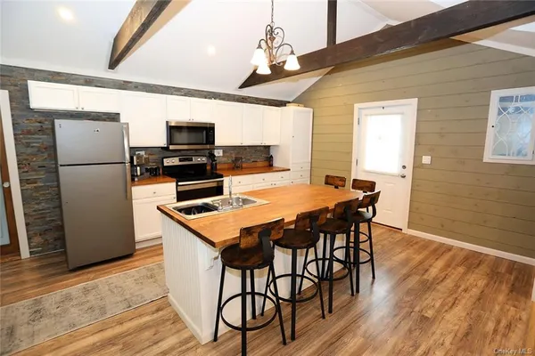 a kitchen with stainless steel appliances a dining table chairs refrigerator and microwave