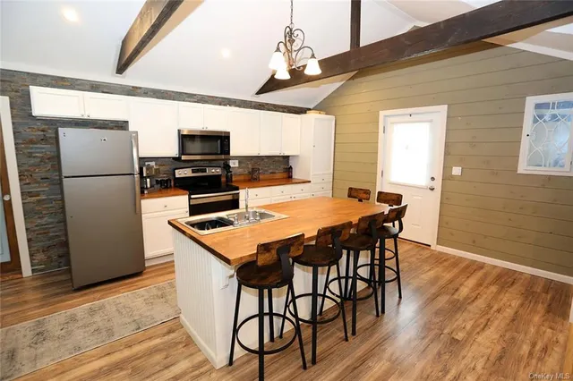 a kitchen with stainless steel appliances a dining table chairs refrigerator and microwave