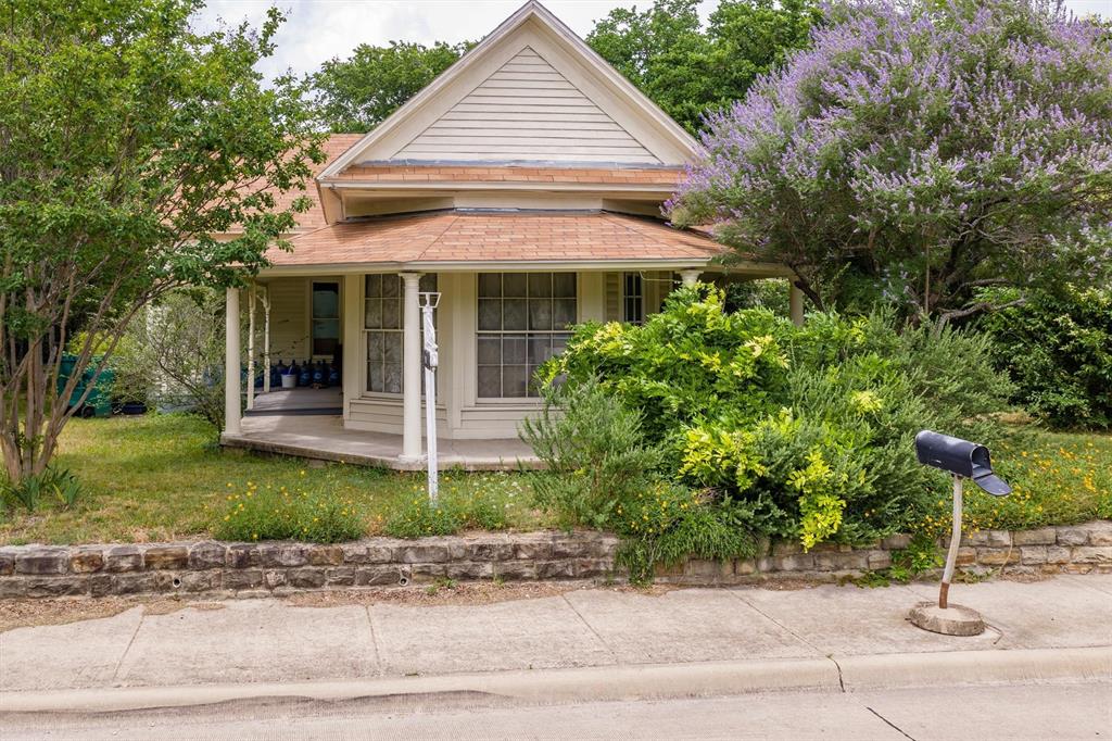 1007 West Belt Line Road Cedar Hill, TX 75104 - Photo 21 of 30 Gable roofline home with horizontal siding, a covered front porch, and a stone retaining wall