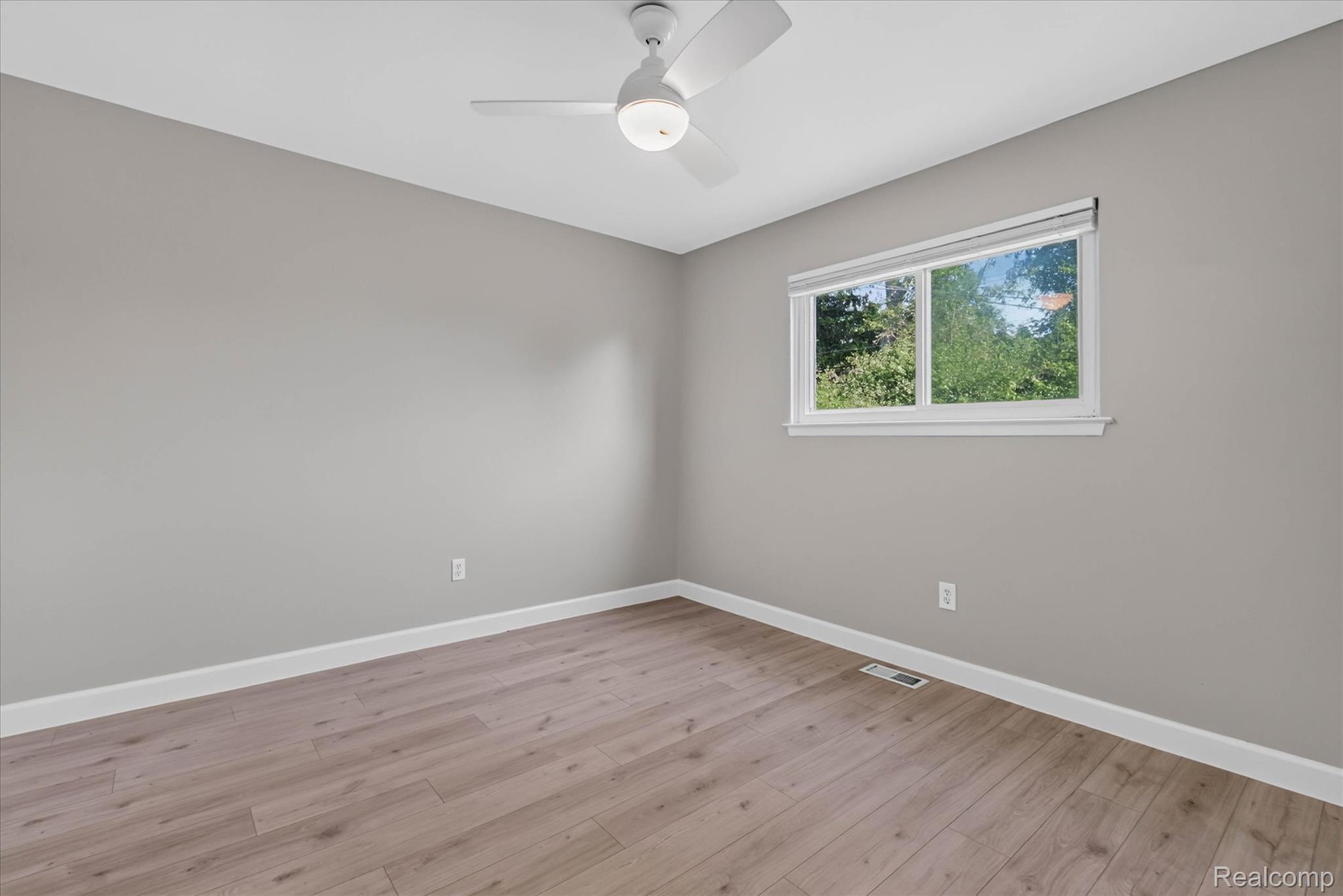 934 Harvard Road Berkley, MI 48072 - Photo 21 of 34 Neutral-toned room featuring a single window, a ceiling fan with integrated lighting, wood-finish flooring, and white baseboards