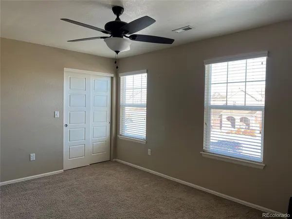an empty room with windows and fan