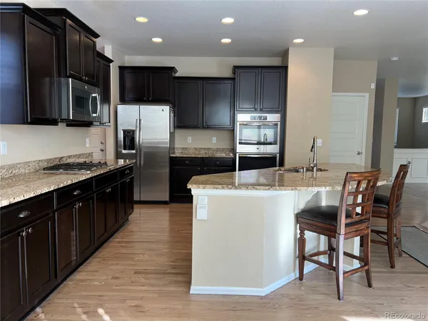 a kitchen with stainless steel appliances kitchen island granite countertop a stove a refrigerator a sink a dining table and chairs