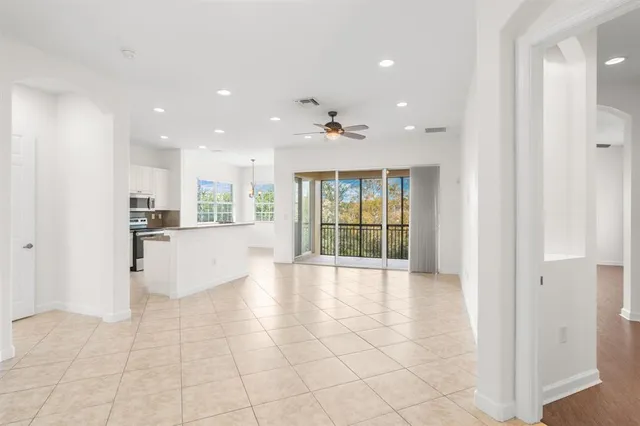 a view of an empty room and kitchen with furniture and large window
