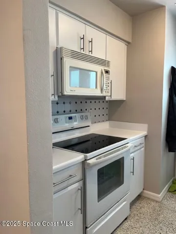 a kitchen with granite countertop white cabinets and white appliances