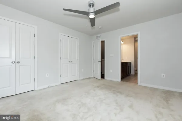 an empty room with closet and a ceiling fan