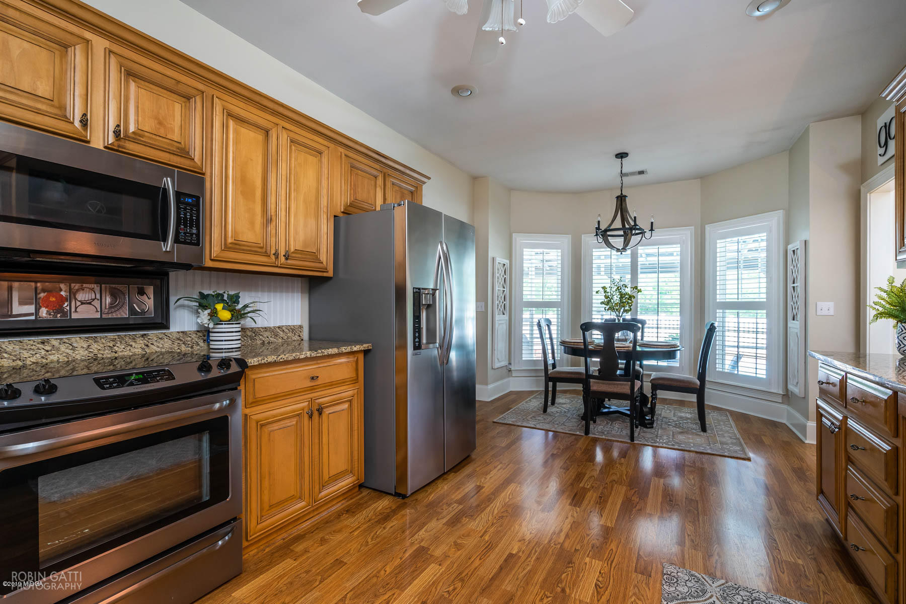 9801 Lower Thomaston Road Macon, GA 31220 - Photo 17 of 40 a kitchen with stainless steel appliances granite countertop a stove top oven a refrigerator a dining table and chairs with wooden floor