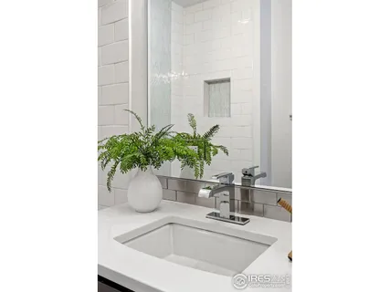 a bathroom with a sink a mirror and a potted plant