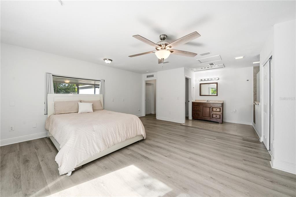 4988 Clarcona Ocoee Road Orlando, FL 32810 - Photo 16 of 48 a spacious bedroom with a large bed and a chandelier