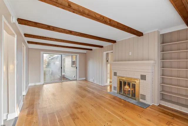 a view of a livingroom with wooden floor and a fireplace