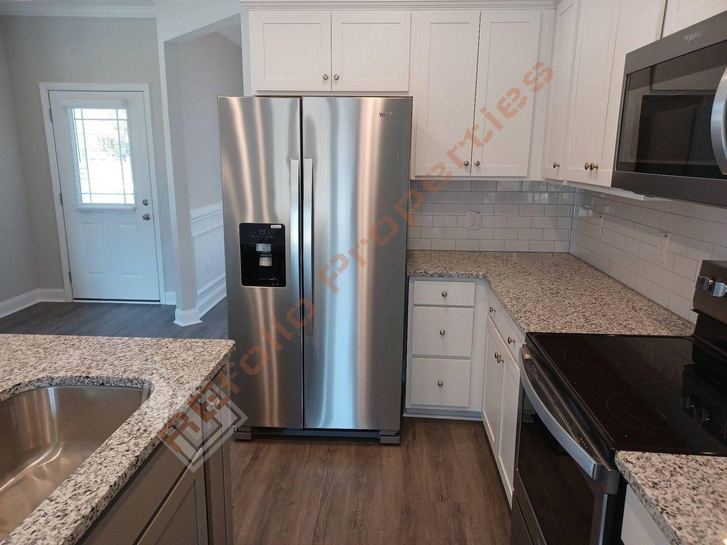 184 Howards Crossing Drive Wendell, NC 27591 - Photo 6 of 29 a kitchen with granite countertop a refrigerator stove and microwave