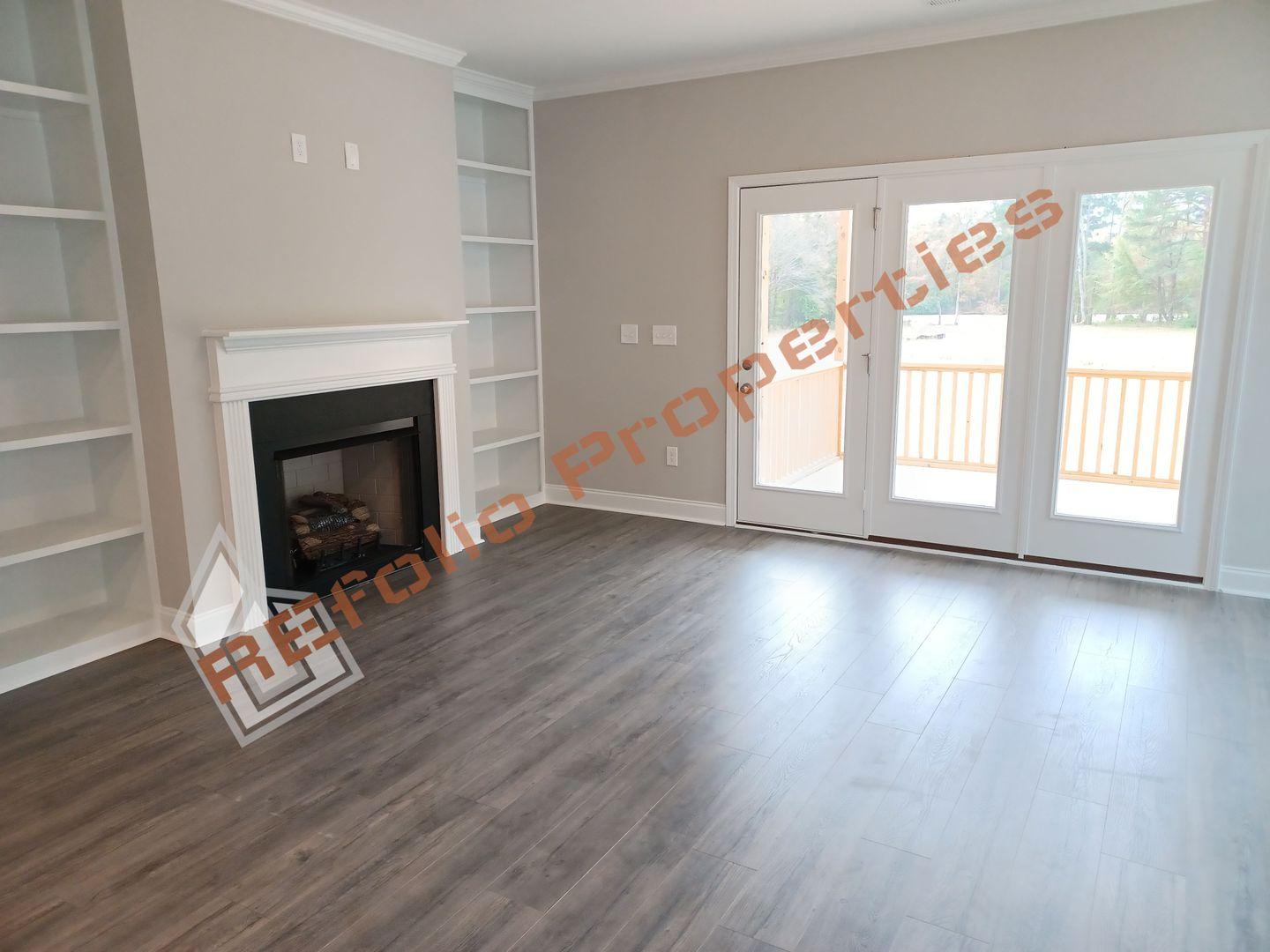 184 Howards Crossing Drive Wendell, NC 27591 - Photo 7 of 29 an empty room with wooden floor fireplace and windows