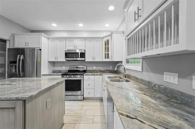 a large kitchen with kitchen island a sink dishwasher stove and white cabinets