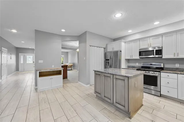 a kitchen with stainless steel appliances granite countertop a refrigerator a stove a sink and a refrigerator