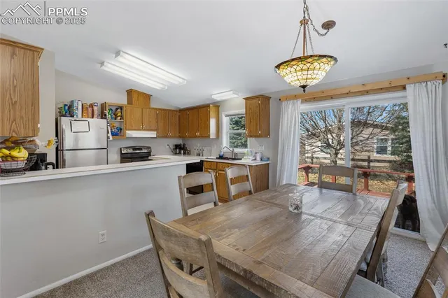 a kitchen with stainless steel appliances a stove a refrigerator a sink a dining table and chairs with wooden floor